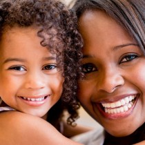 young african american mother and daughter smiling while looking at camera