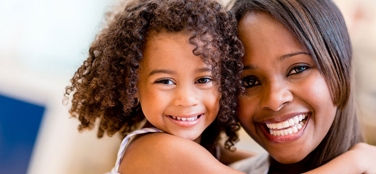 young african american mother and daughter smiling while looking at camera