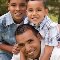 young hispanic father and his two sons pose for family portrait outdoors