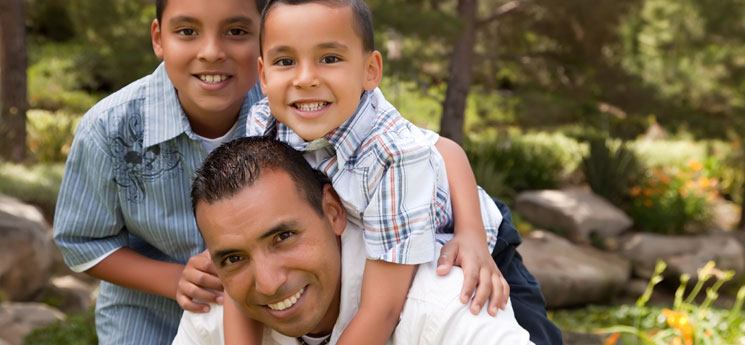 young hispanic father and his two sons pose for family portrait outdoors