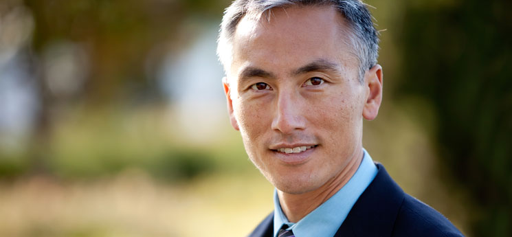 middle aged asian man in suit looking at camera