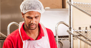 man wearing apron and hair net while working in industrial kitchen