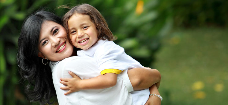 hispanic mother holding and hugging her young son while smiling