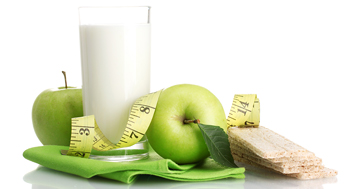 glass of milk with green apples, tape measurer, healthy crackers and green cloth napkin