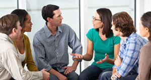 six adults sitting in circle deep in conversation