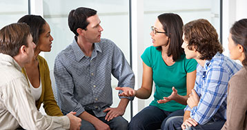 six adults sitting in circle deep in conversation