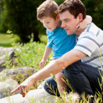 father with young boy outdoors by a stream