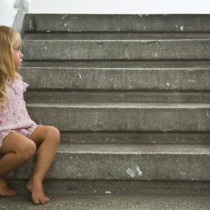 young, barefoot homeless girl sitting on steps
