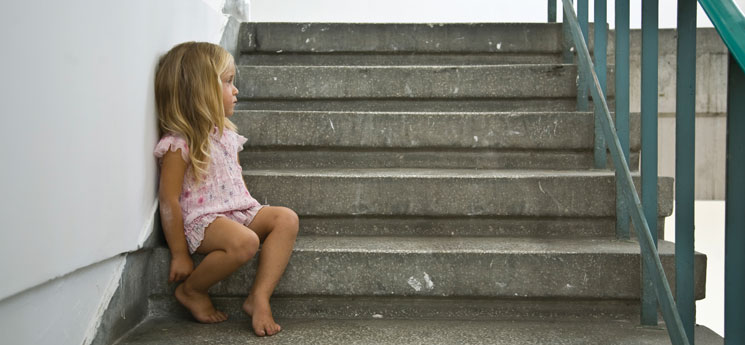 young, barefoot homeless girl sitting on steps